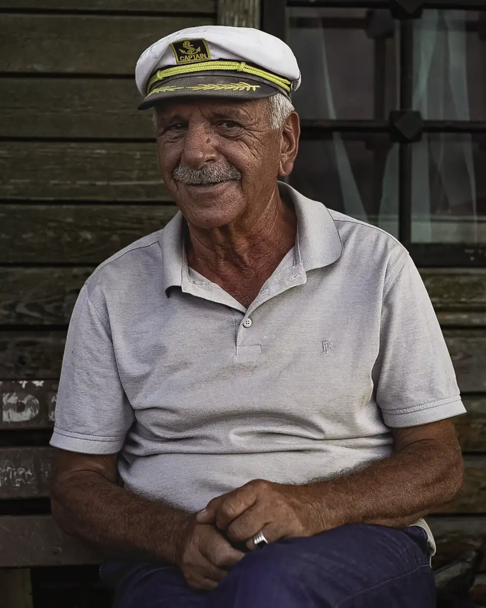 Older man in a captain's hat smiling