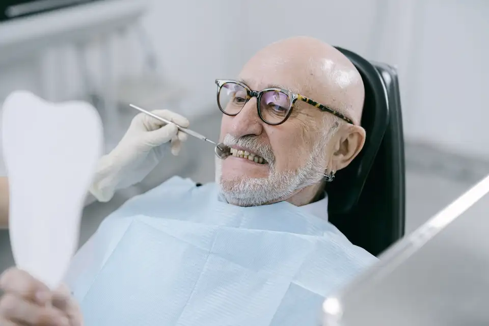Older man checking his smile in a dentist's mirror